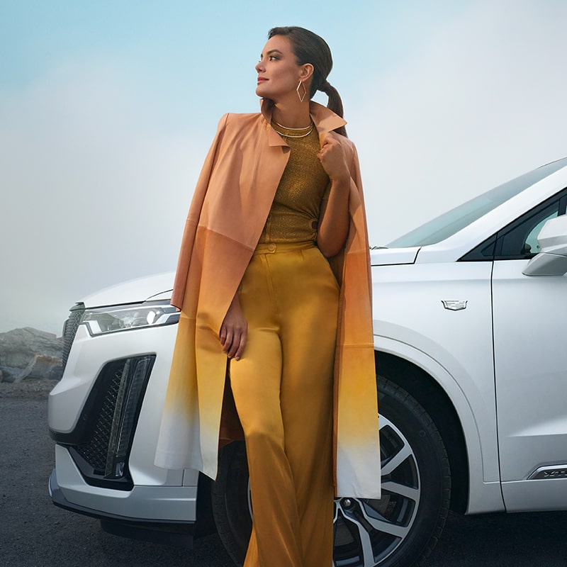 A Fashionable Woman Leans Up Against Her Cadillac XT6