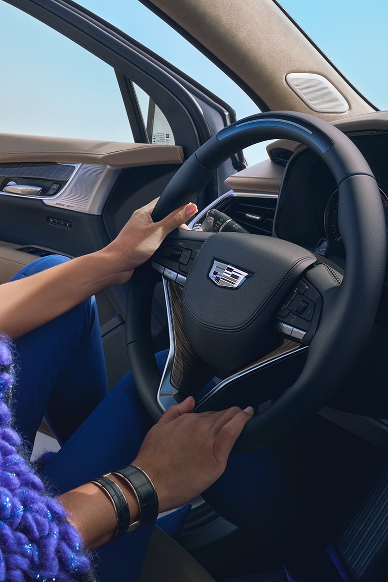 A Woman Uses Both Hands to Hold onto the Steering Wheel As She Exits Her Cadillac XT6