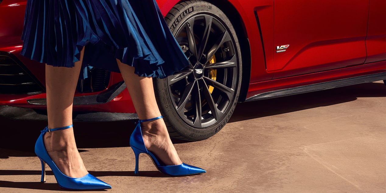 A Woman Wearing a Blue Dress & Blue Heels Walks Alongside the CT4-V