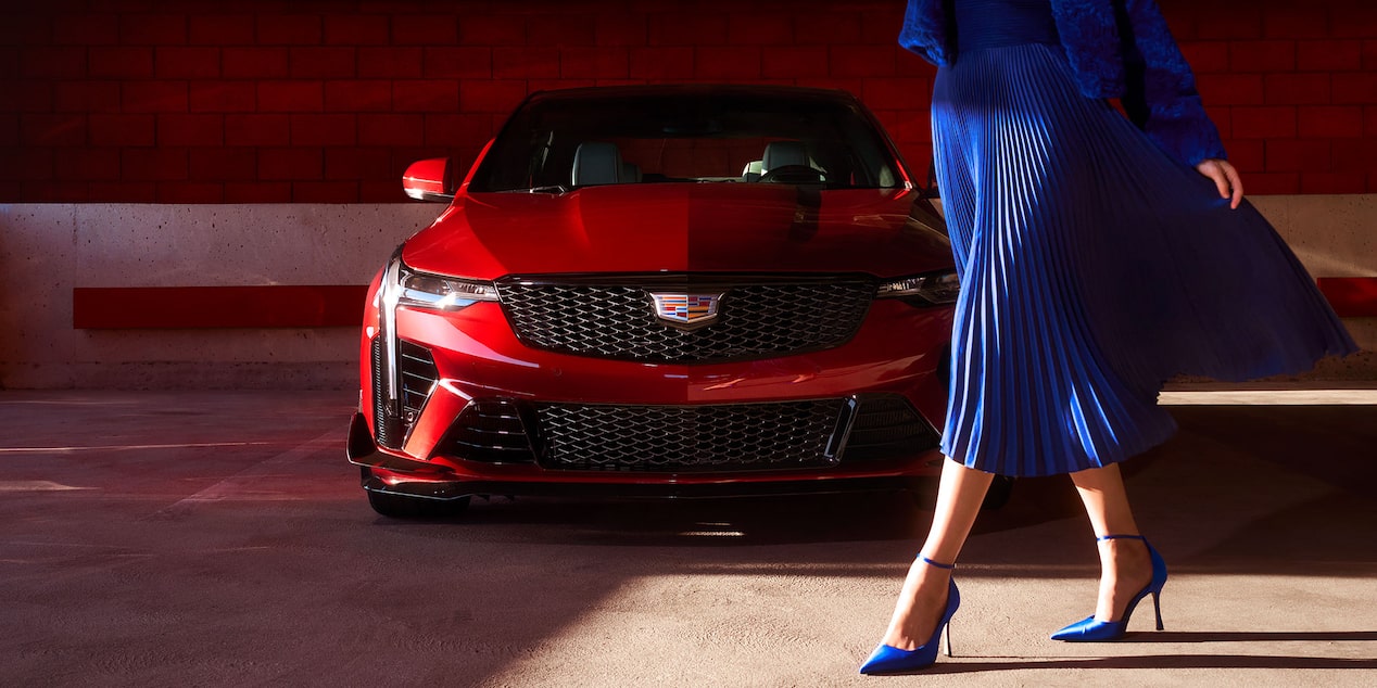 A Woman in a Blue Dress Walking Infront of a Cadillac CT4-V While Parked in a Garage