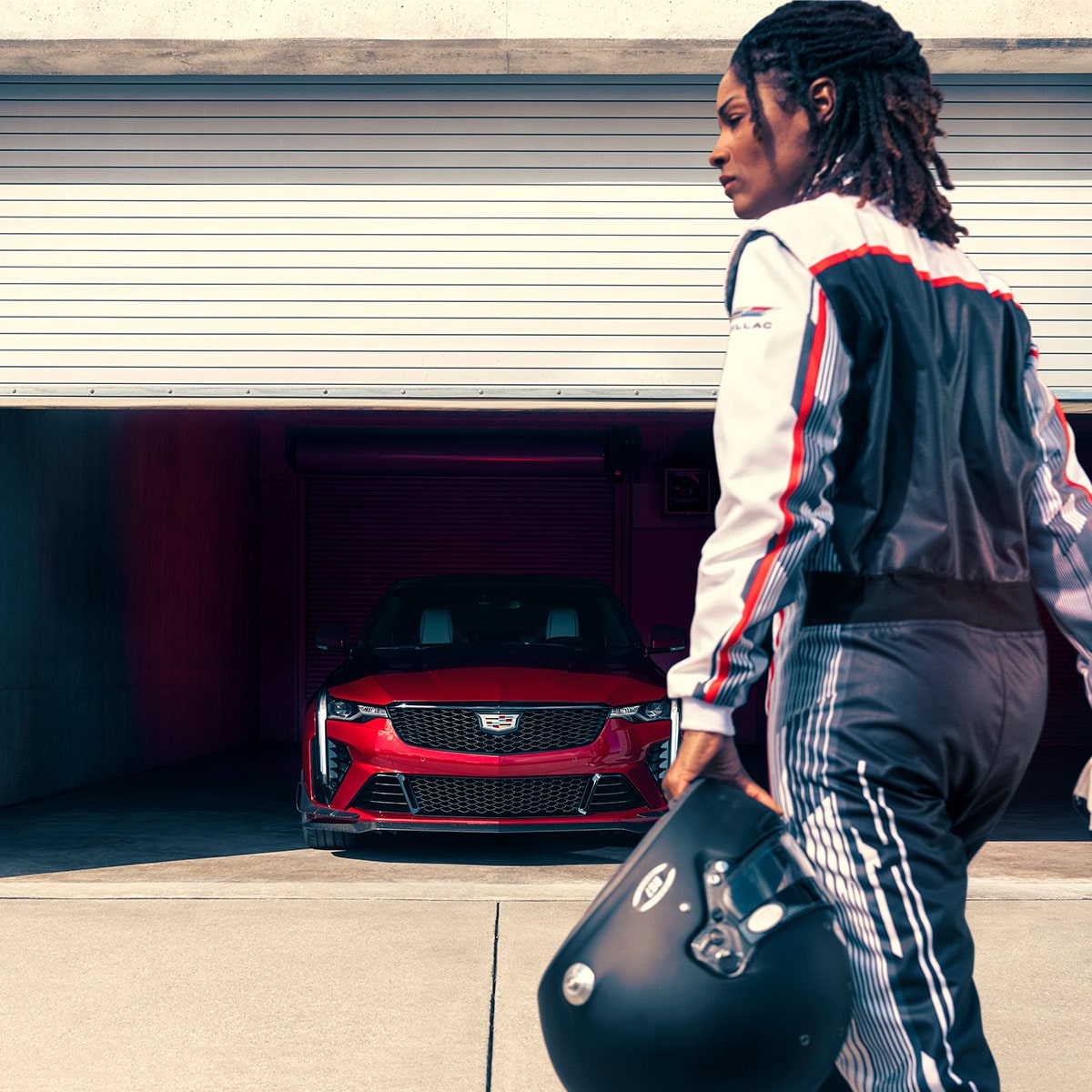 A Woman Holding a Helmet Approaches a CT4-V in a Partially Opened Garage