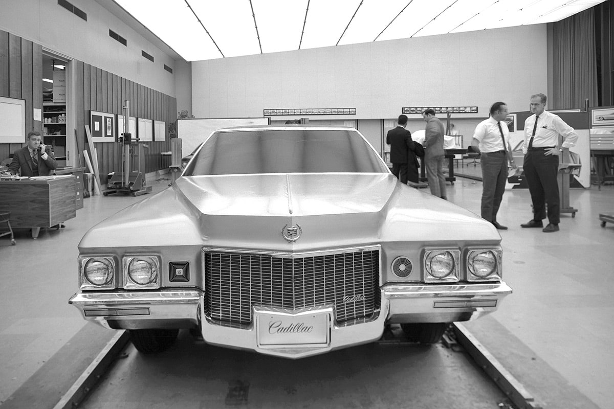 Cadillac clásico en la sala de exposición con hombres de pie alrededor
