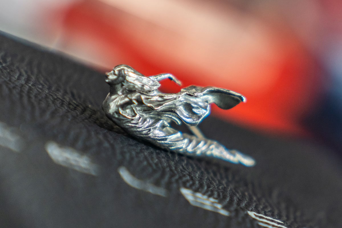 A Close-up View of the Intricate Silver Cadillac Mascot Sculpture, the Spirit of Ecstasy, Resting on a Black Textured Surface.