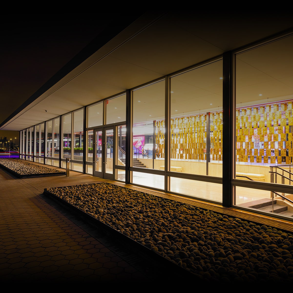 An Exterior Night Shot of the Modern Cadillac House at Vanderbilt Building with Large Glass Windows.