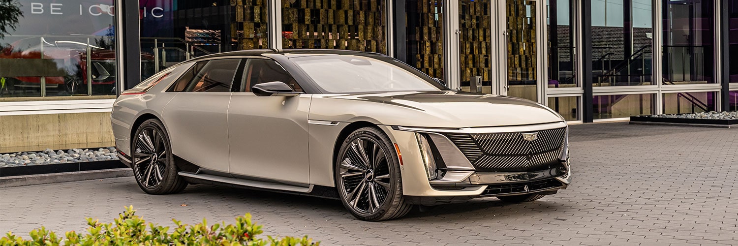 The Front of a Light Metallic Gold Cadillac CELESTIQ Parked Outside a Modern Building During the Day.