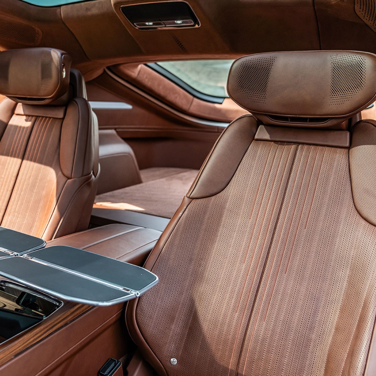 The Rear Interior of the Cadillac CELESTIQ, Featuring Brown Leather Seats and an Open Foldable Tray Table.
