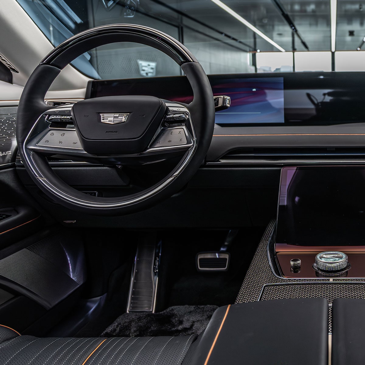 The Side Profile of the Dark Gray Cadillac CELESTIQ Parked on a Glossy Floor, with Be Iconic on the Wall in the Background.