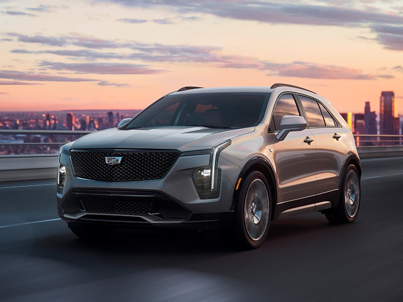 Cadillac XT4 2025 cruzando un puente, con la ciudad a la distancia, durante un atardecer