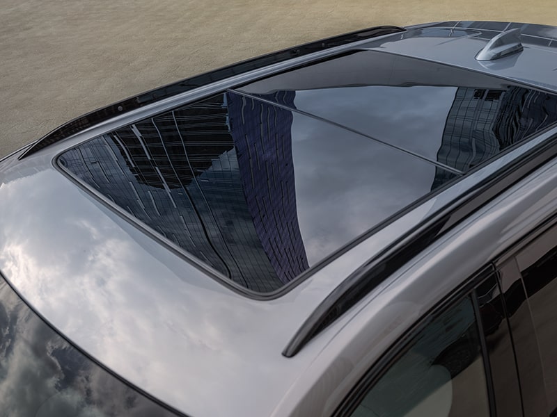 El enorme techo corredizo de Cadillac XT4 2025 reflejando las nubes en el cielo