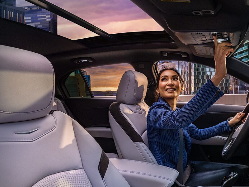 Una mujer activa el techo corredizo eléctrico con doble vidrio de una Cadillac XT4 2025 en la ciudad