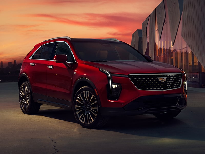 Cadillac XT4 2025 en Rojo estacionada cerca de un edificio industrial, durante un hermoso atardecer