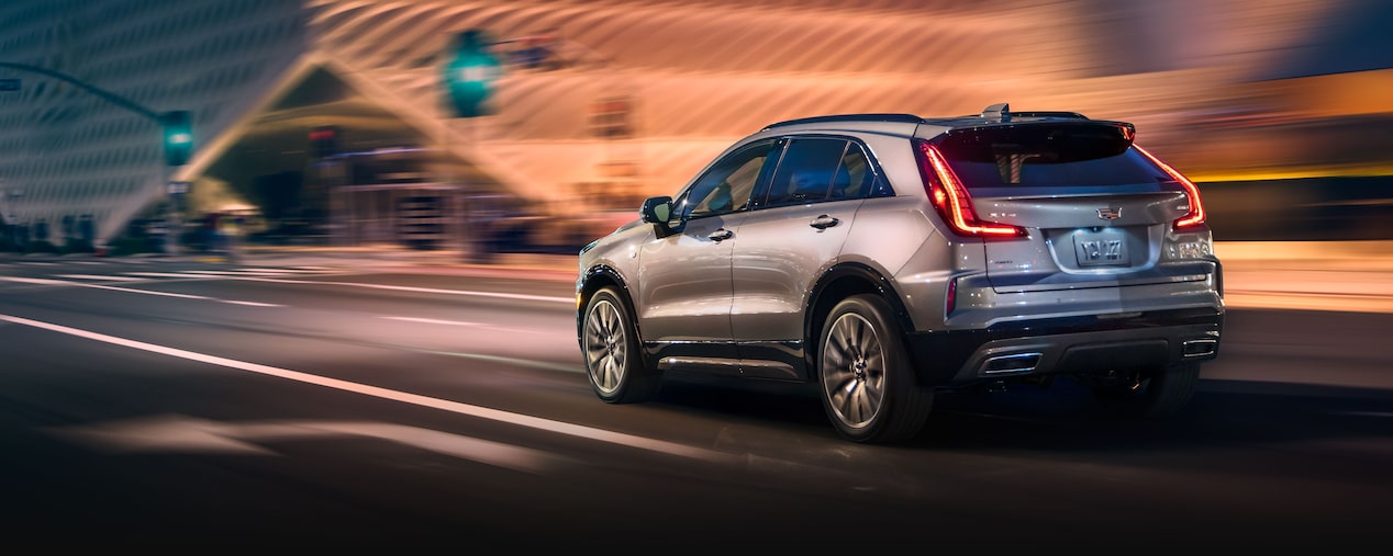 Vista trasera de la Cadillac XT4 2025 circulando rápidamente por una ciudad de noche