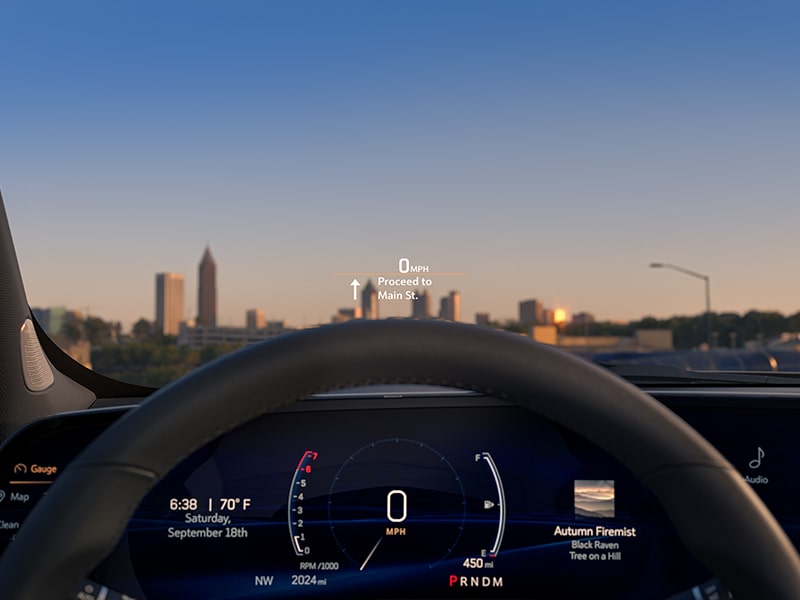 Primer plano de Head-up Display de Cadillac XT4 2025 en el parabrisas, con una vista de la ciudad