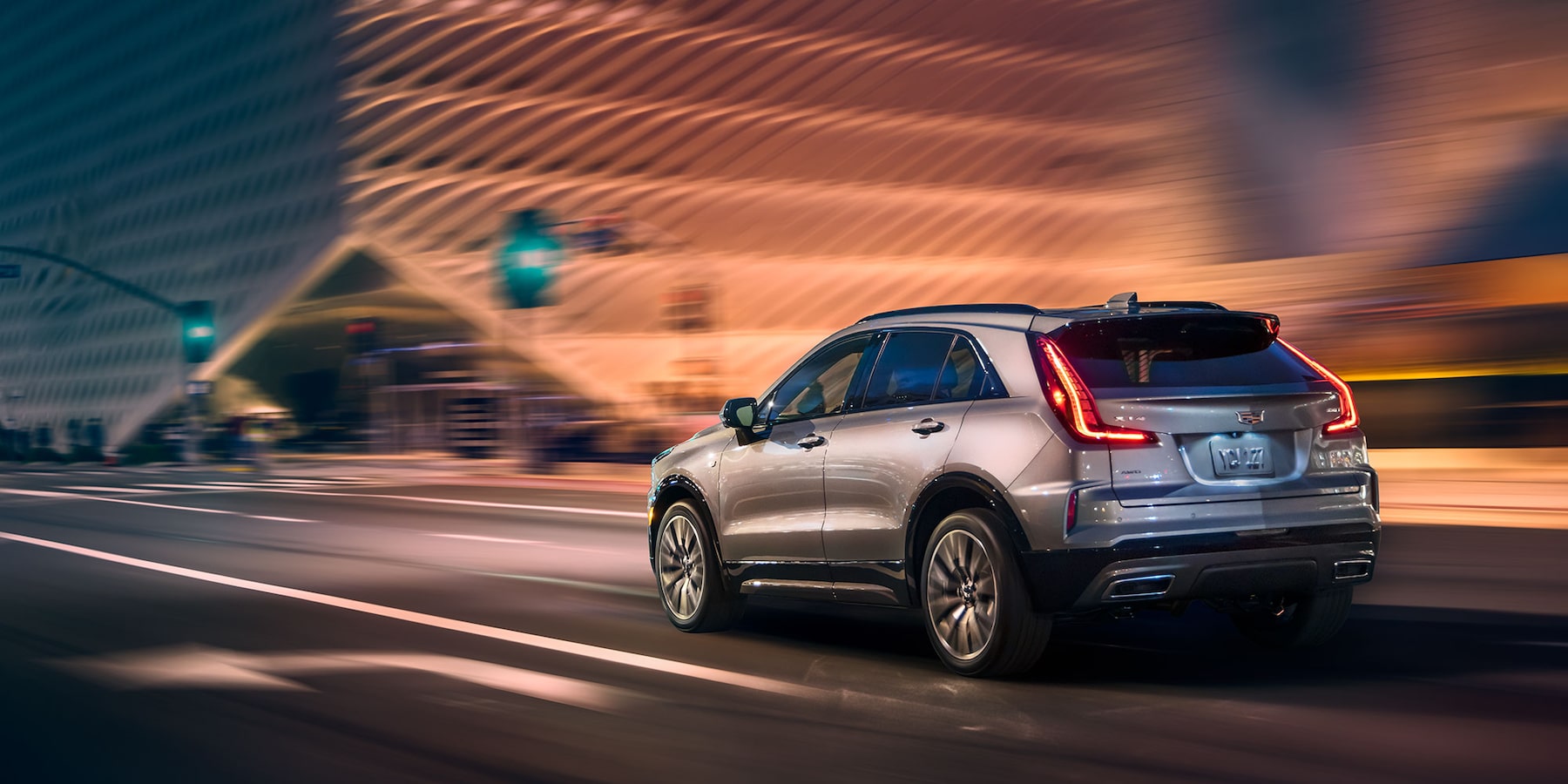 Rear view of the New Cadillac XT-4 with 18 inch spoke wheels driving down highway at night