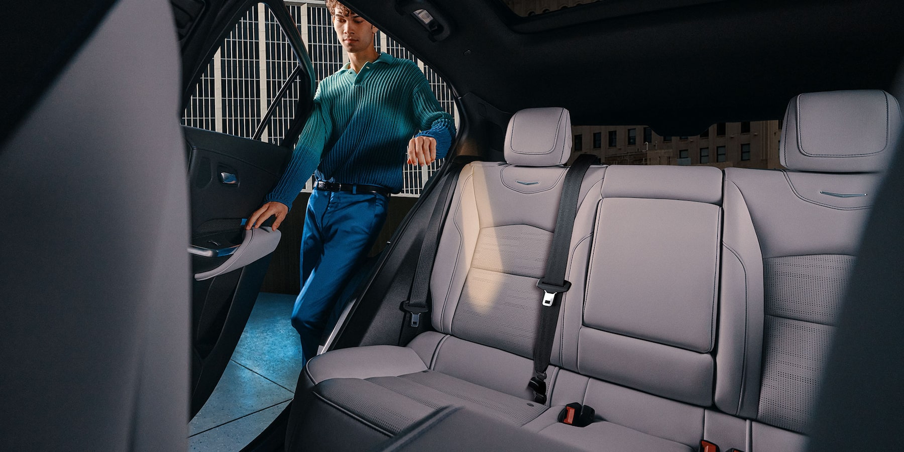 Man getting into the wide 3 person backseat of a 2025 Cadillac XT-4 with white leather interior