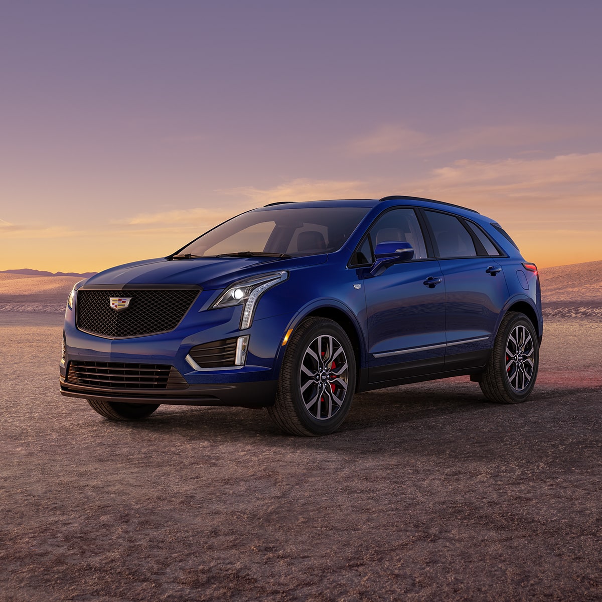 Una Cadillac XT5 en Azul Luna Oscuro Metálico estacionada al atardecer, en el desierto