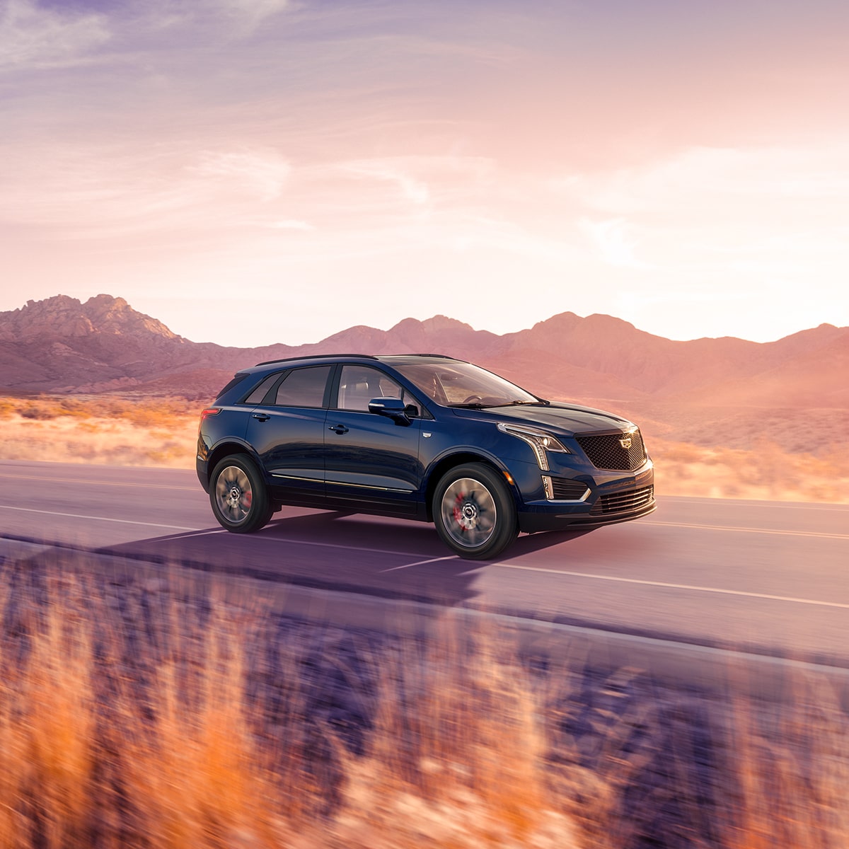 Cadillac XT5 2025 en Azul Oscuro circulando por un camino occidental durante el crepúsculo