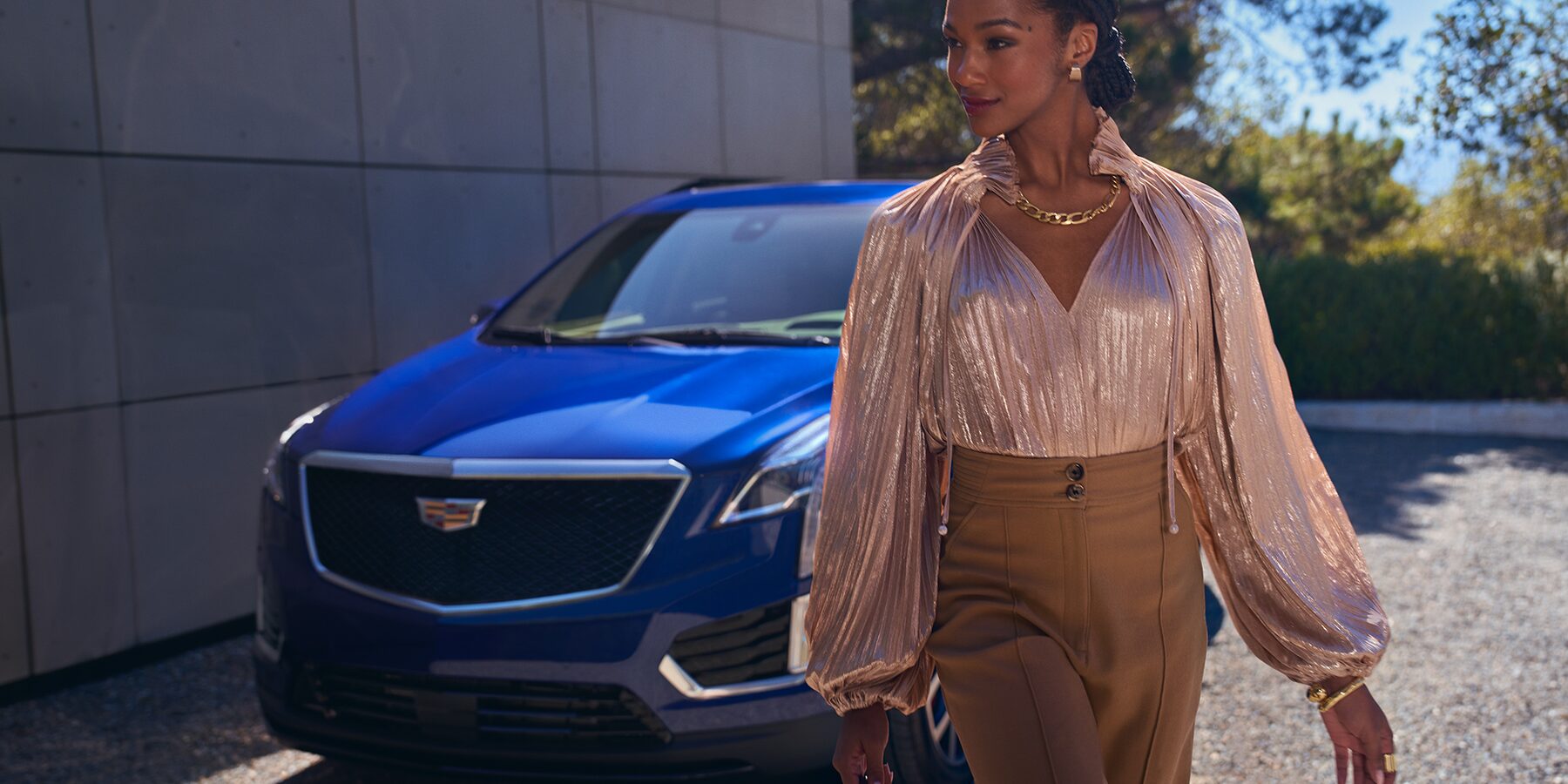 Fashionable woman walking away from a blue exterior Cadillac XT5 sport