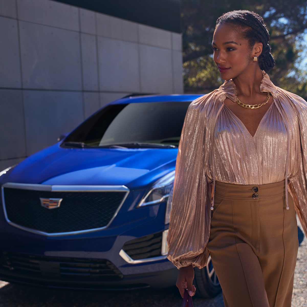 Mujer vestida a la moda alejándose de su Cadillac XT5 2025 estacionada