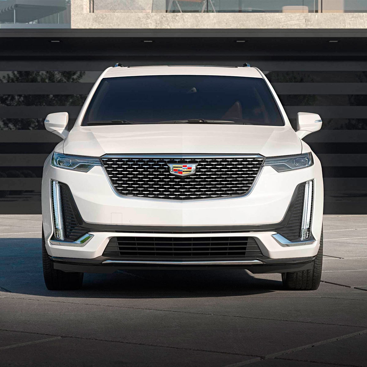 Una Cadillac XT6 en Blanco Cristal Tricapa estacionada en una entrada de garaje