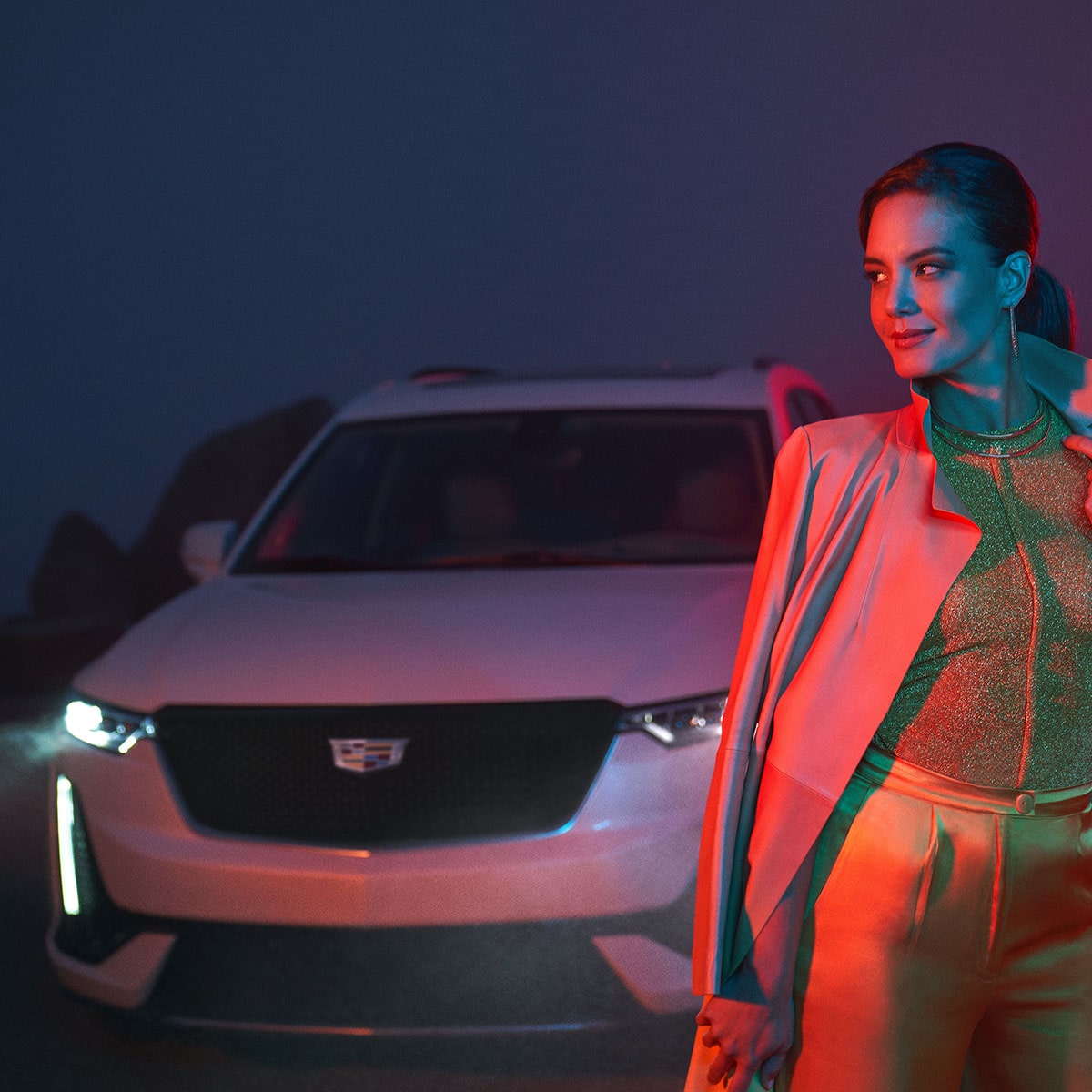 Una mujer posa en frente de una Cadillac XT6 durante la noche