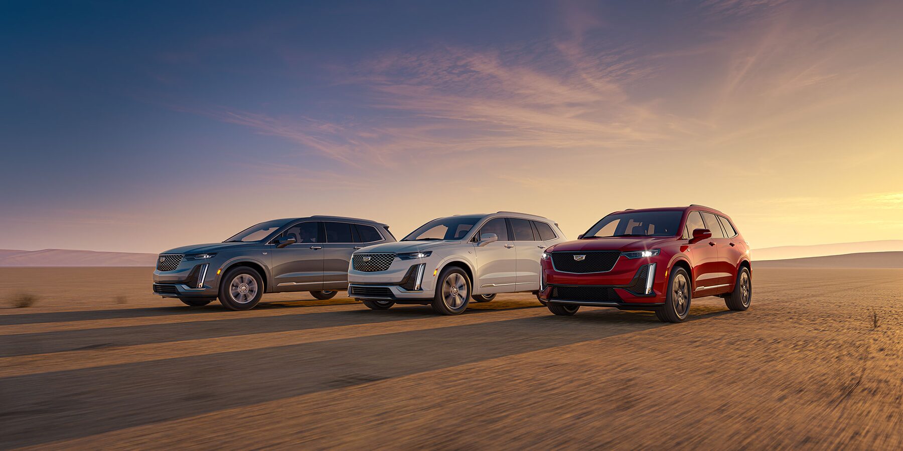 2025 Grey, White and Red Cadillac XT6 SUV's driving next to each other along a dry desert terrain