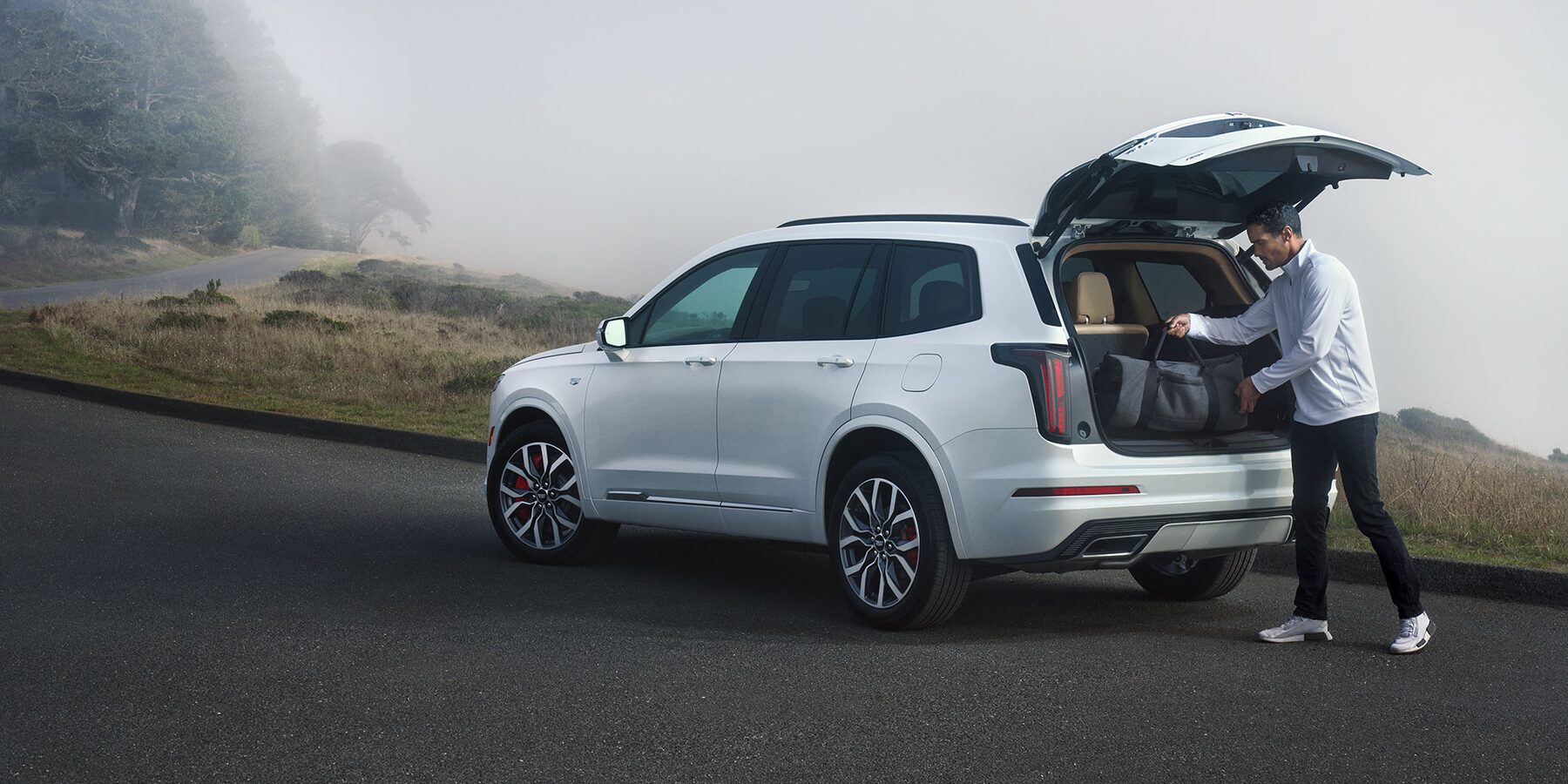 Man loading his Cadillac XT6 Luxury Mid-Sized SUV with duffel bag inside the 78.7 cubic ft trunk