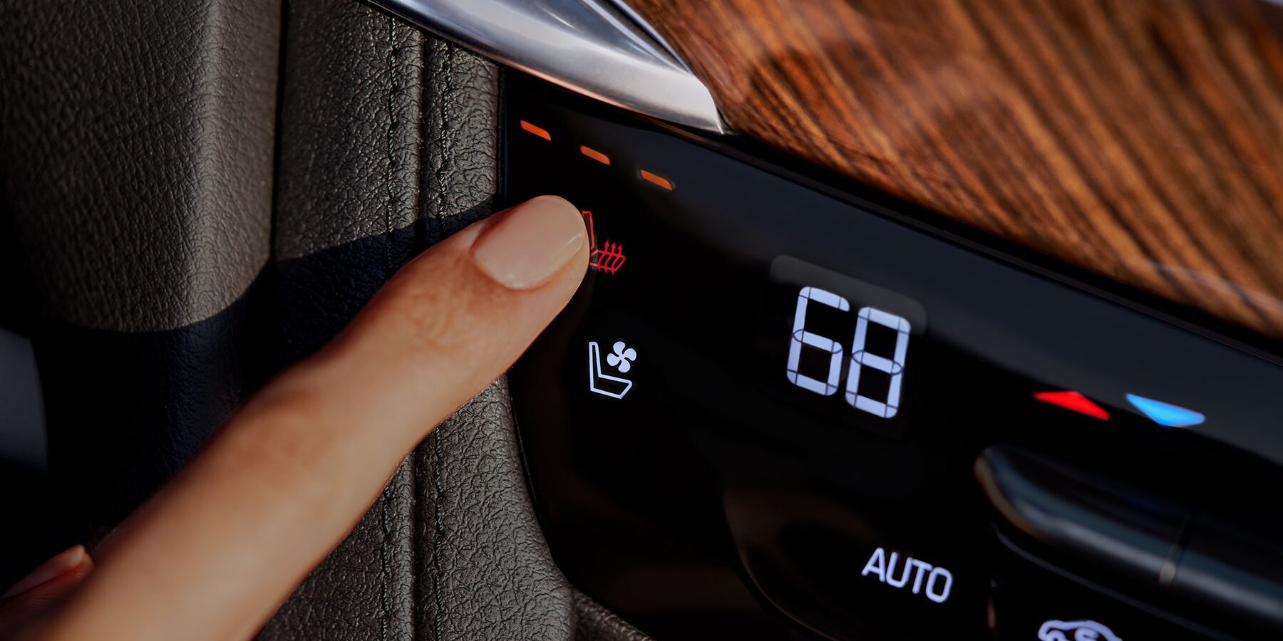 A person finger pressing the heated seat button inside the 2025 Cadillac XT6