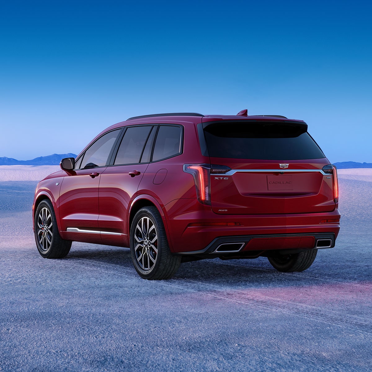 Vista difuminada de una Cadillac XT6 circulando por un camino despejado con una vista increíble de las montañas