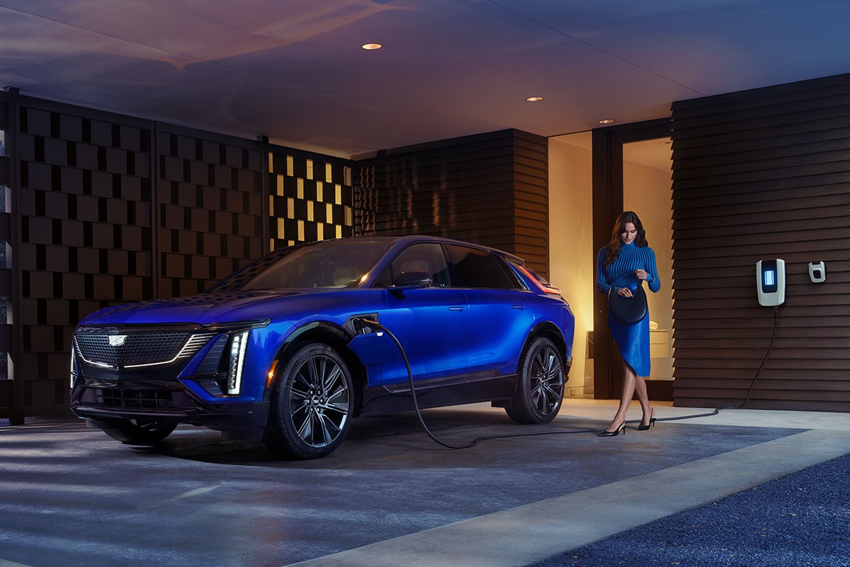 A Woman Looking in Her Purse Next to a Charging Blue 2025 Cadillac LYRIQ