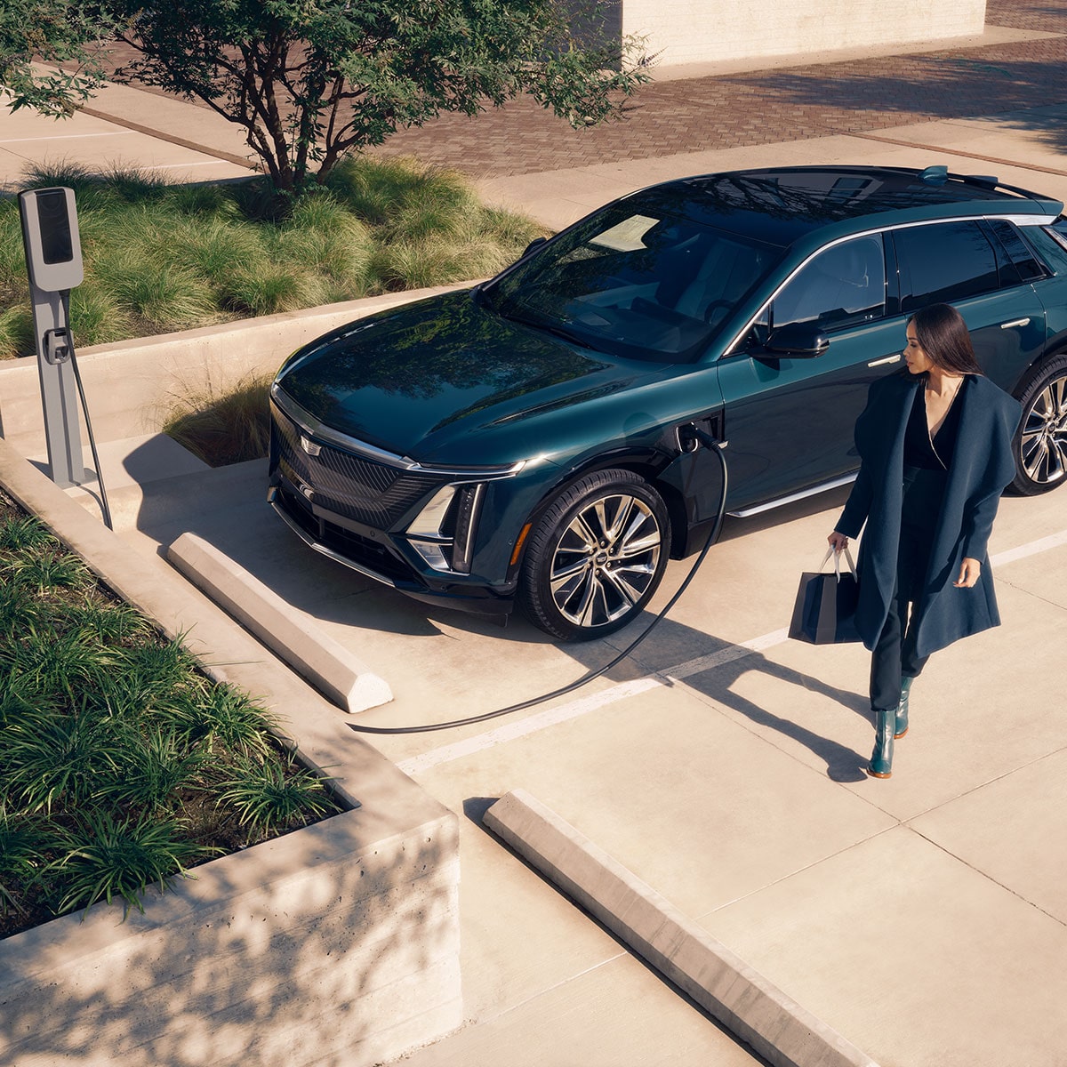 A Business Woman Walking Away From a Cadillac LYRIQ While it Charges at a Public EV Charger