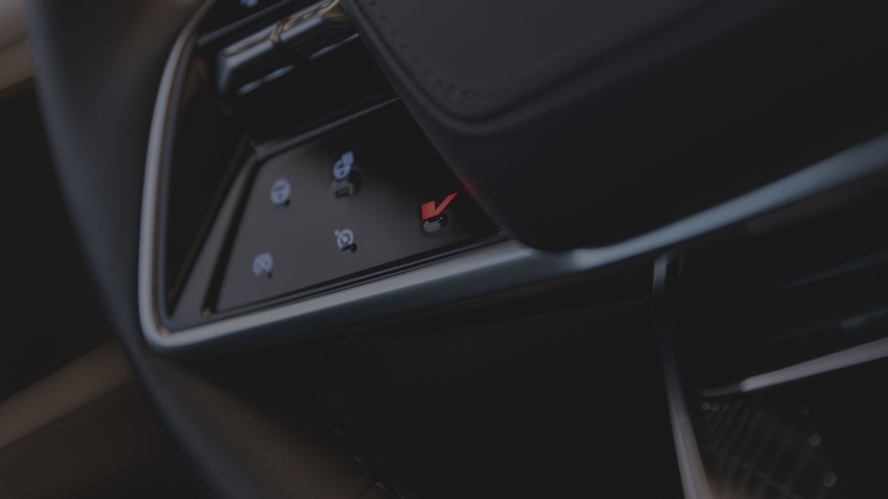 A Close-Up View Of A Cadillac LYRIQ Steering Wheel Showing Illuminated Touch-Sensitive Control Icons Beside the Lower Spoke.