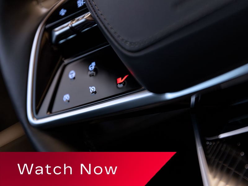 A Close-Up View Of A Cadillac LYRIQ Steering Wheel Showing Illuminated Touch-Sensitive Control Icons Beside the Lower Spoke.