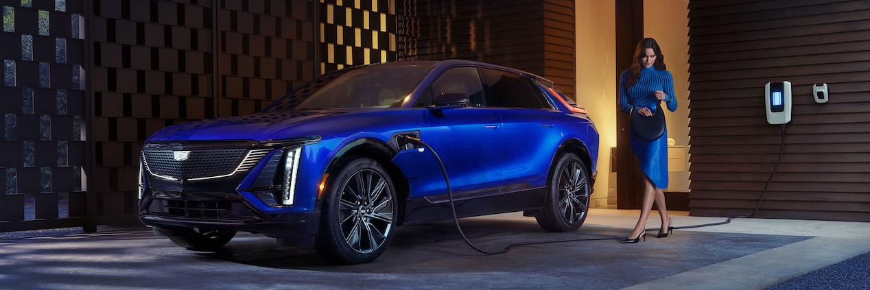 A Woman Looking in Her Purse Next to a Charging Blue 2025 Cadillac LYRIQ