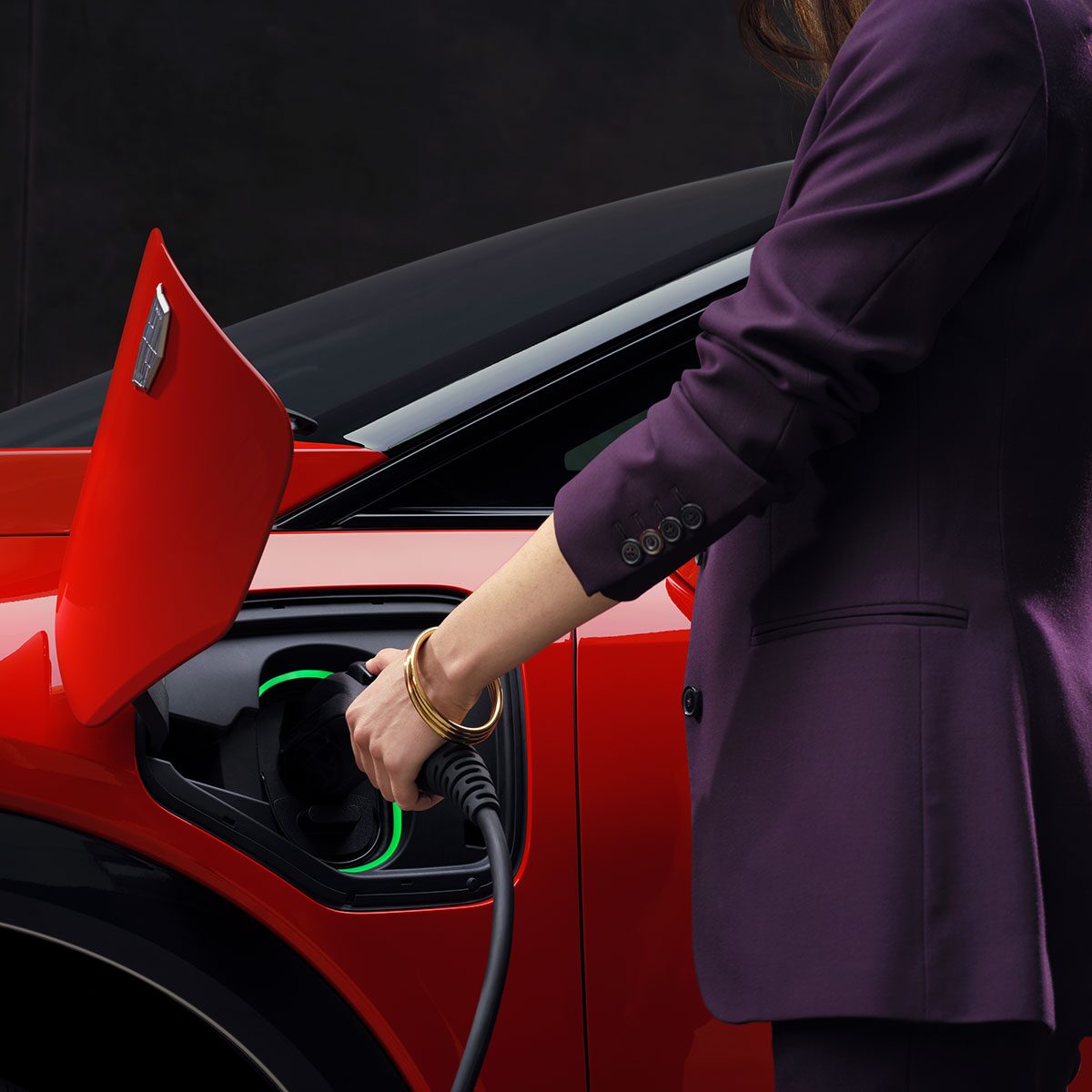 A Man Holding a Phone and Looking at the 2025 OPTIQ Range in the myCadillac Mobile App