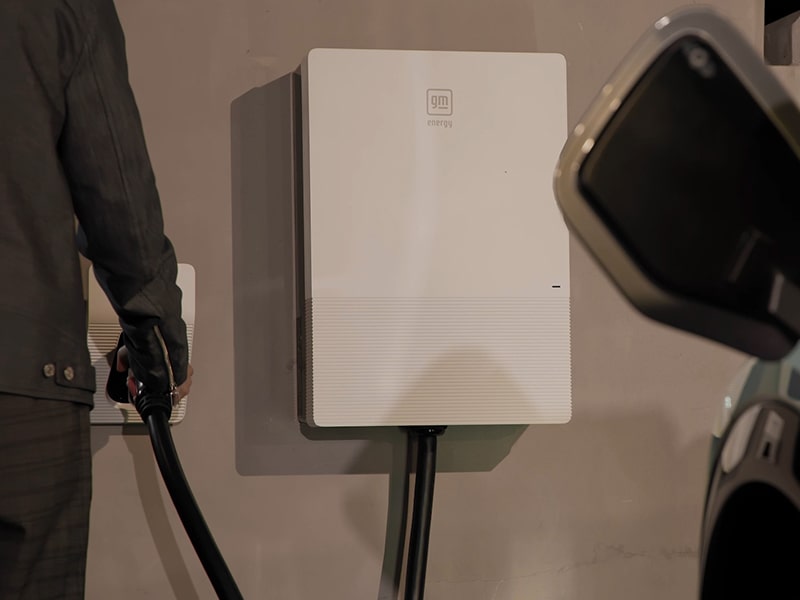 Un hombre usando el cargador residencial GM Energy para cargar una Cadillac OPTIQ 2025