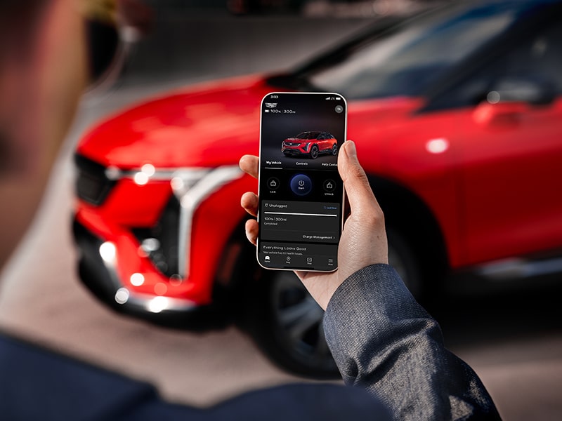 Un hombre que sostiene un teléfono y mira la autonomía de OPTIQ 2025 en la aplicación móvil myCadillac