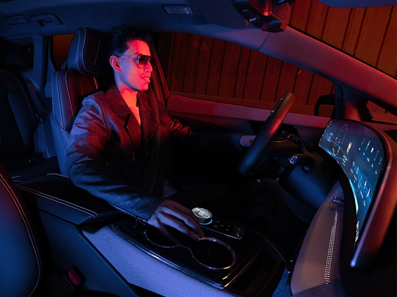 Vista del acompañante de un hombre que conduce Cadillac OPTIQ 2025 en un semáforo en rojo