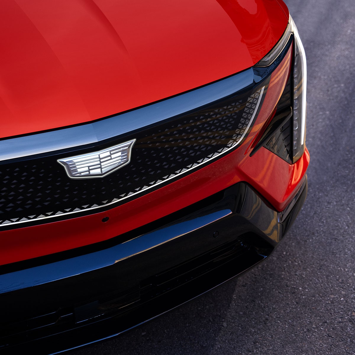Close-up View of a Red 2025 Cadillac OPTIQ's Grille and Headlamp