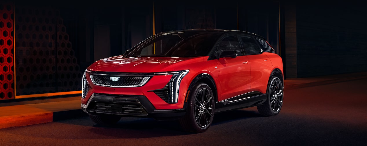 Vista de medio perfil de Cadillac OPTIQ 2025 en Rojo estacionada en una calle oscura