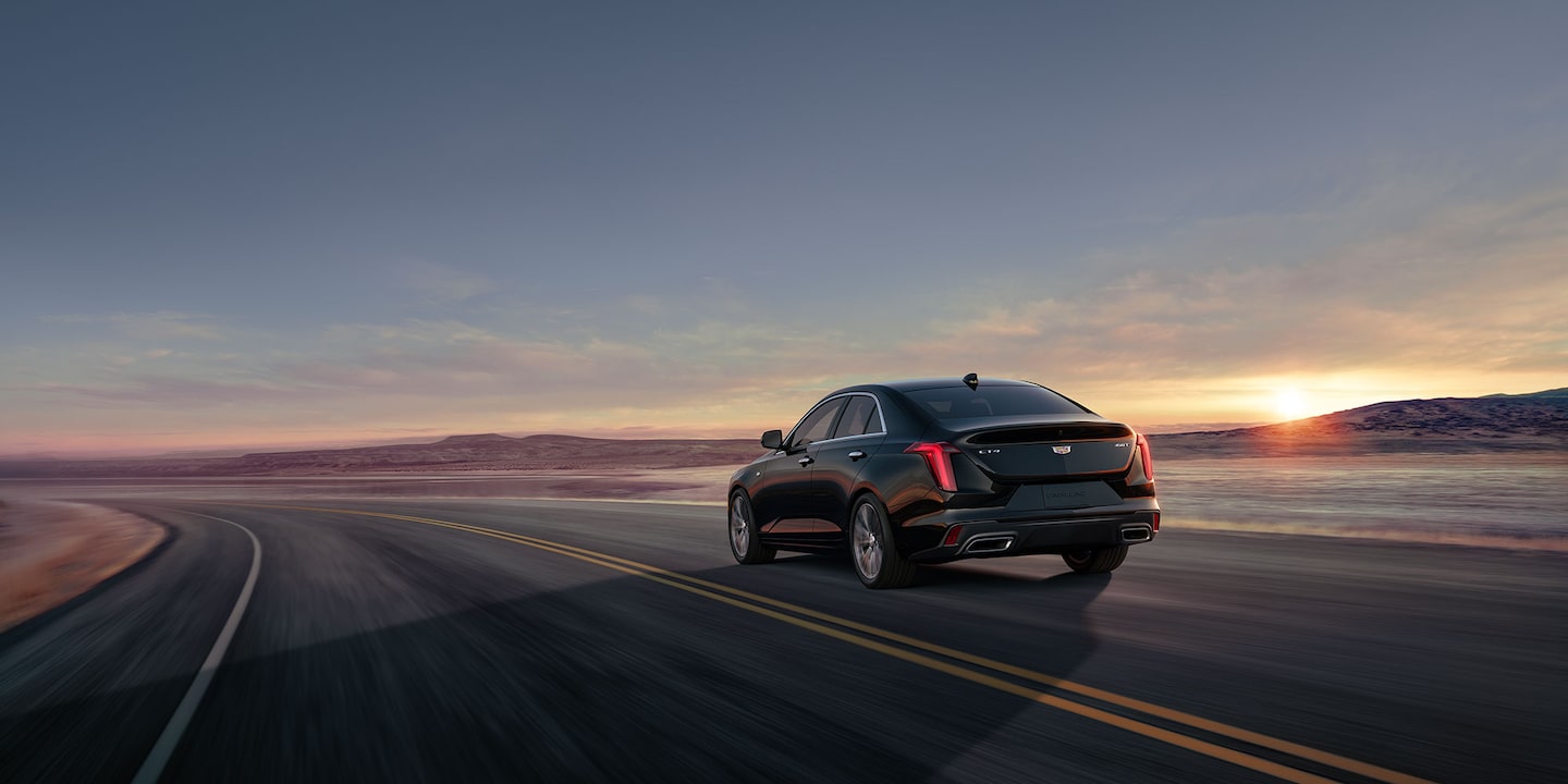 Rear view of black 2025 Cadillac CT-4 driving off into the sunset