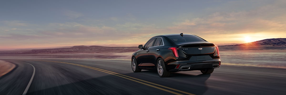 Three Quarters Rear View of a Black 2025 CT4 Driving Down a Desert Road