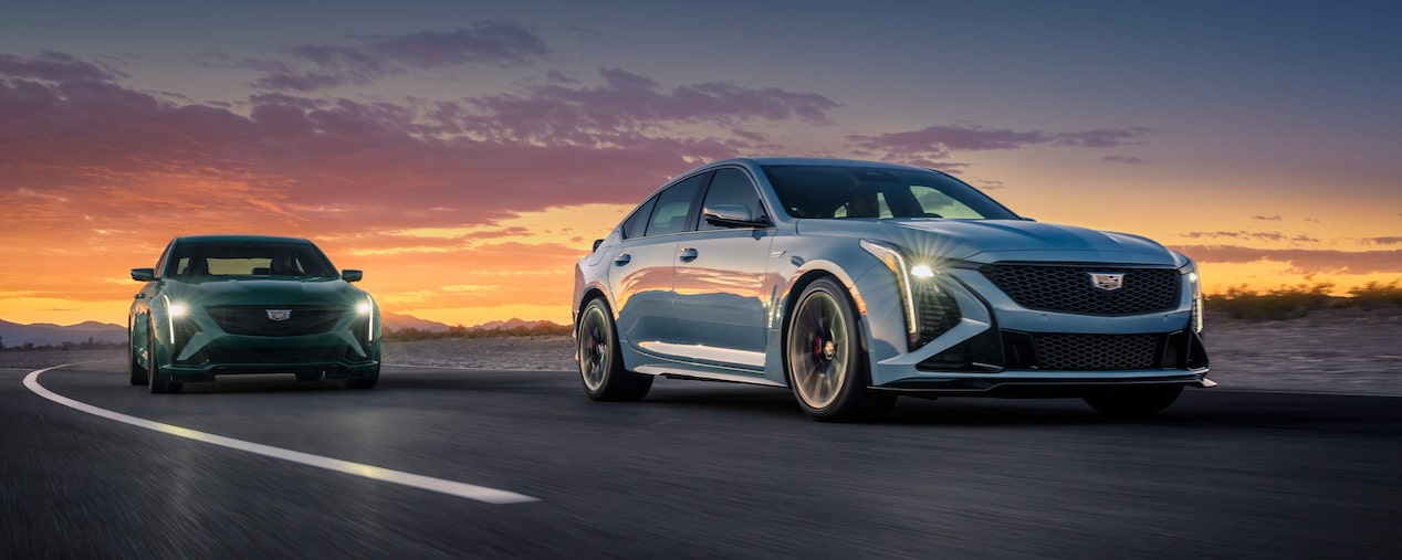 Three-Quarters View of Two 2025 Cadillac CT5-V Driving on a Road Under an Evening Sky