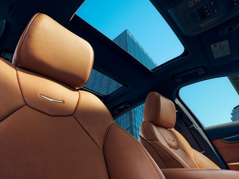 Sun Shining on 2025 Cadillac CT5 Crest on Front Leather Seats and View of Sun Roof