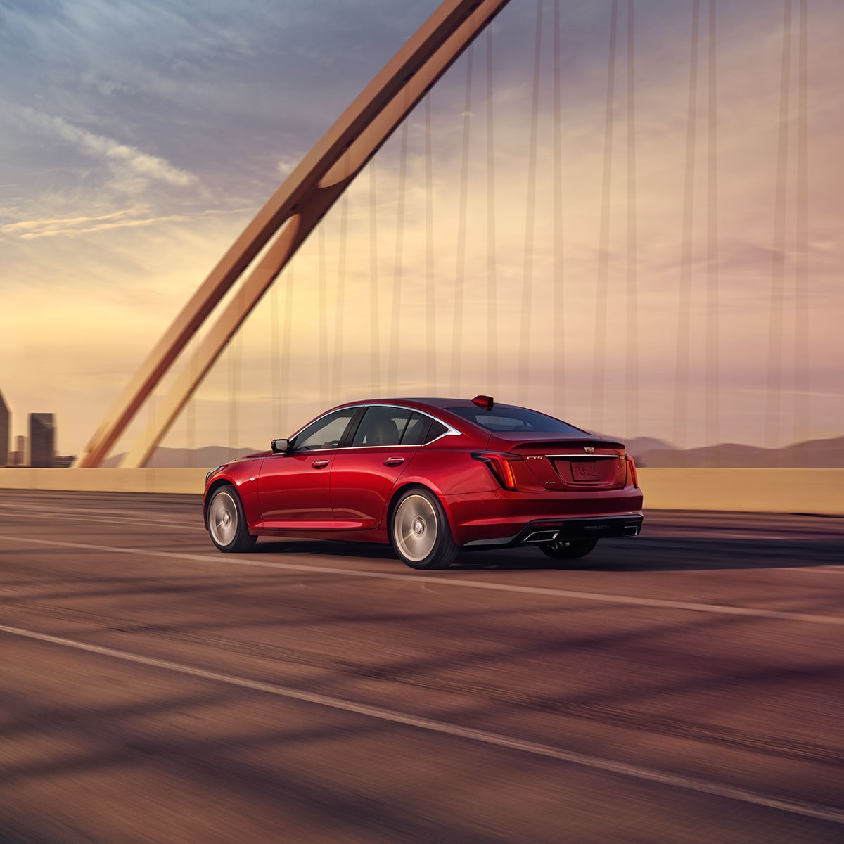 Side View of a Radiant Red Tintcoat 2025 Cadillac CT5 Driving on Bridge