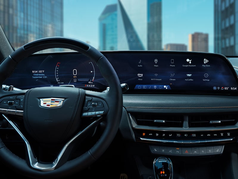 The 2025 Cadillac CT5 Steering Wheel and View of 33" Display Screen Outlooking Industrial Buildings