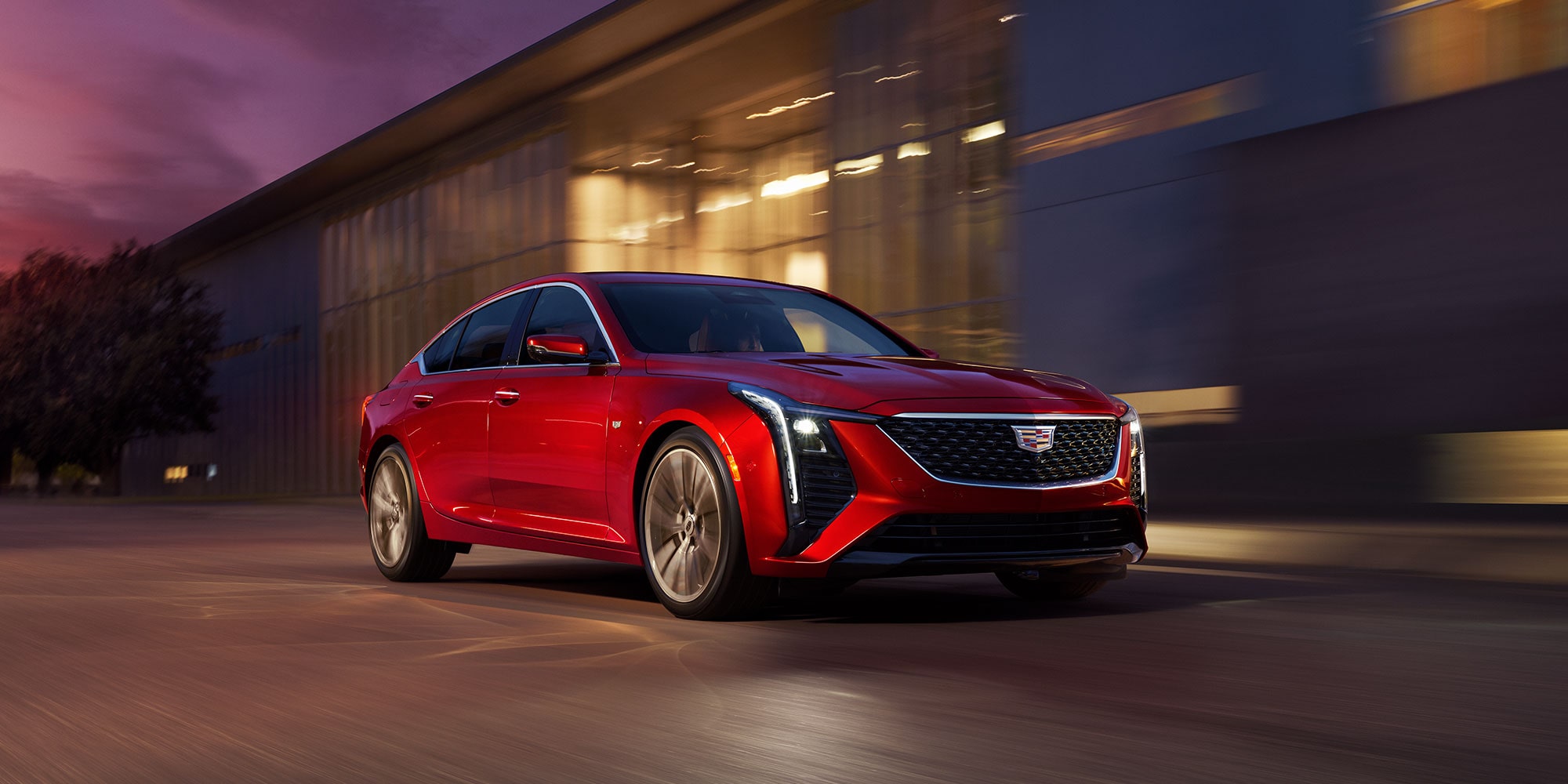2025 Cadillac CT-5 in red driving in front of building