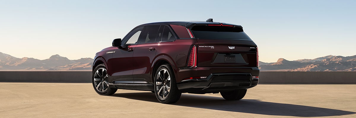 Three-quarters Rear End View of a Maroon 2026 ESCALADE IQ Parked in the Desert