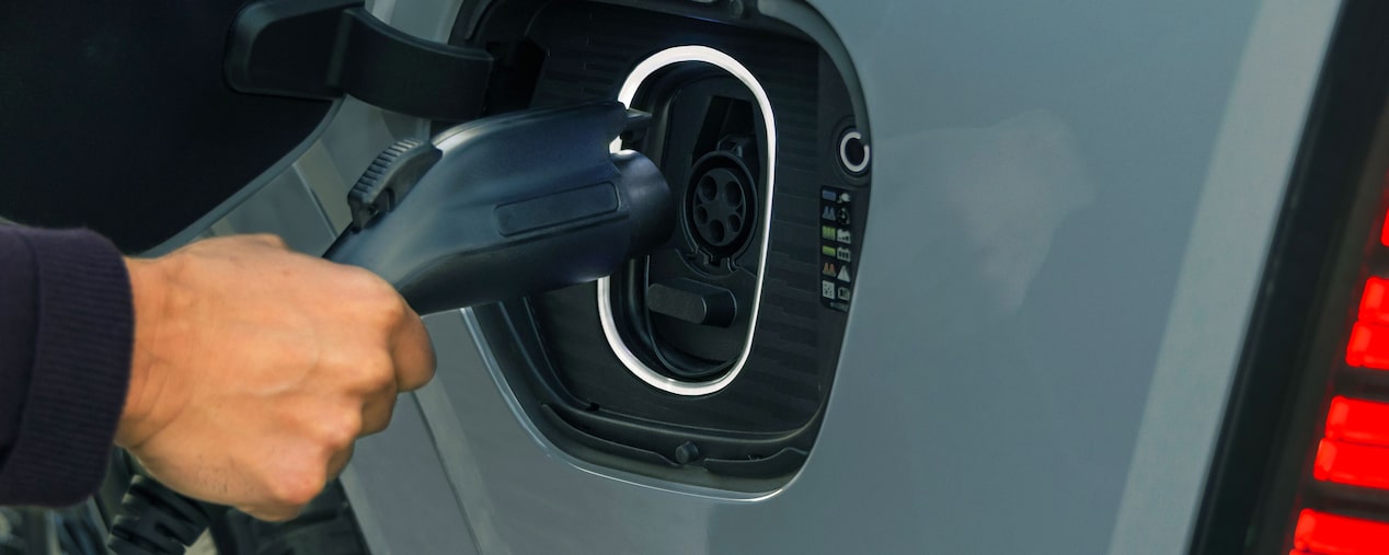 Primer plano de alguien insertando el cargador de EV en el puerto de ESCALADE IQL 2026