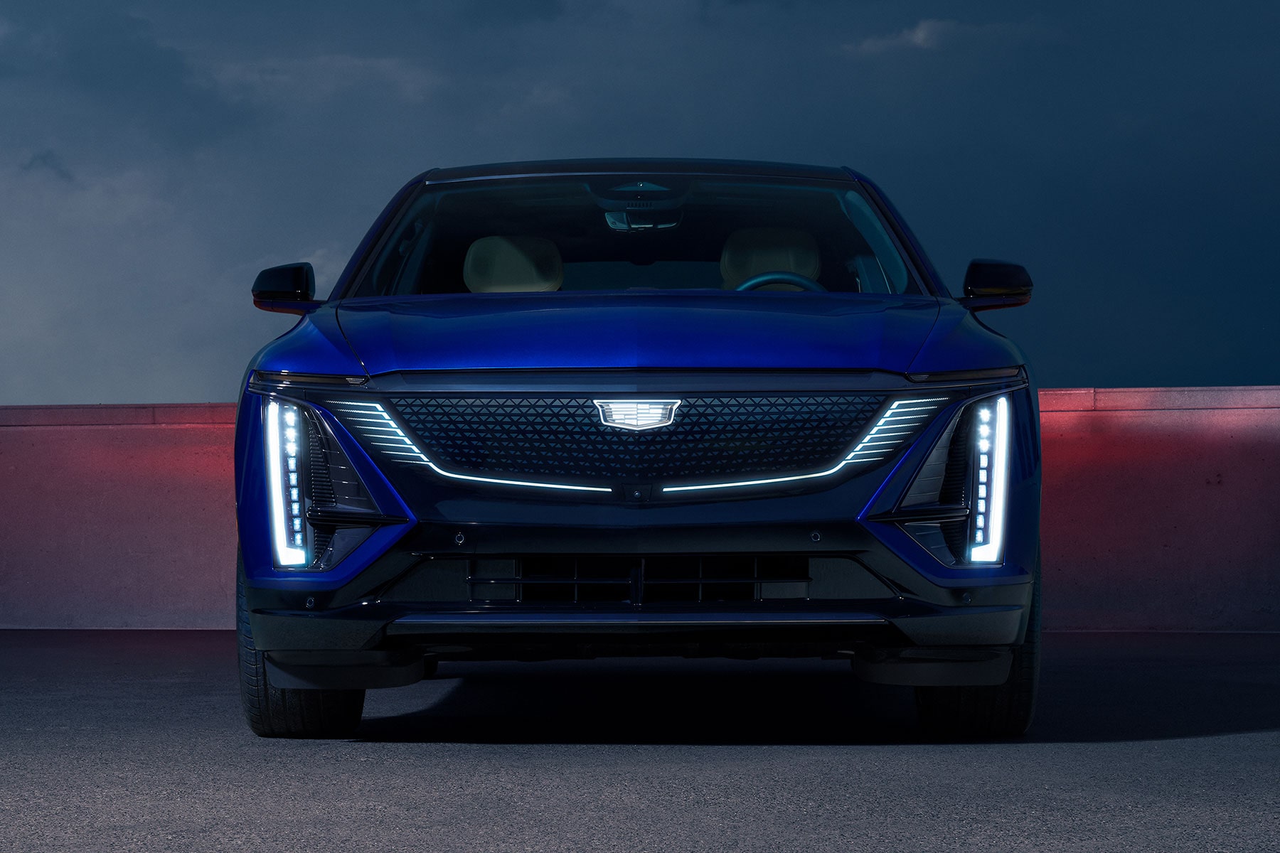 Front View of a Blue 2027 Cadillac LYRIQ With Illuminated Vertical LED Signature Lighting and an Illuminated Grille.